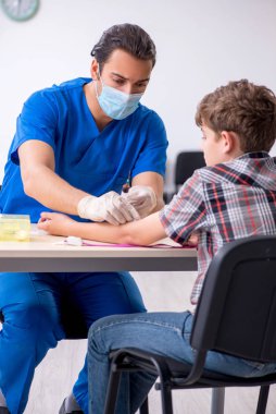 Genç çocuk hastanede doktoru ziyaret ediyor.