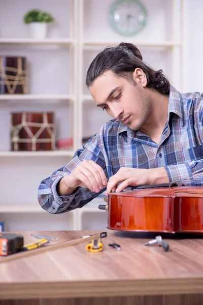 Молодой красивый ремонтник чинит виолончель — стоковое фото