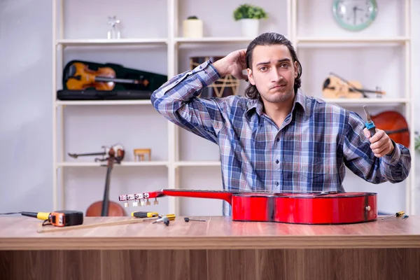 Giovane bello riparatore riparazione chitarra — Foto Stock