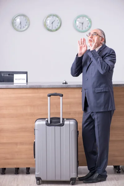 Old businessman at the hotel reception — Stock Photo, Image