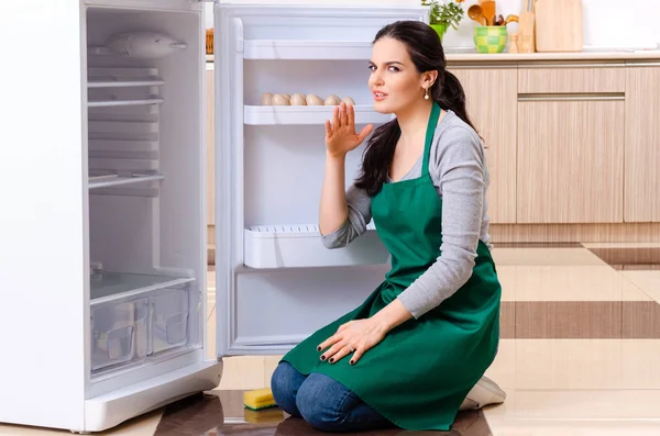Молодая женщина моет холодильник в концепции гигиены — стоковое фото
