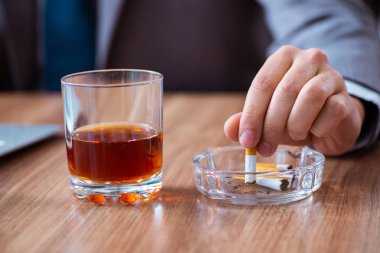 İş yerinde alkol ve sigara içen bir erkek işçi.