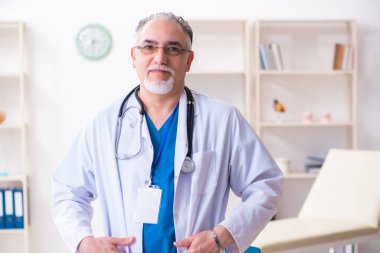 Klinikte çalışan yaşlı erkek doktor.