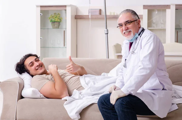 Velho médico visitando jovem paciente masculino — Fotografia de Stock