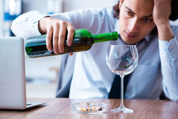 Männlicher Angestellter trinkt Alkohol und raucht Zigaretten am Arbeitsplatz — Stockfoto