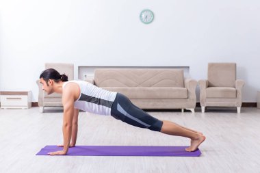 Genç adam evde antrenman ve egzersiz yapıyor.