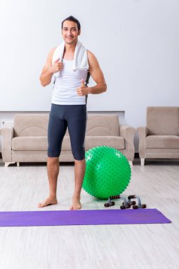 Genç adam evde antrenman ve egzersiz yapıyor.