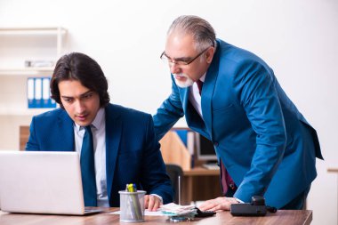 Genç ve yaşlı çalışanlar ofiste birlikte çalışıyorlar.