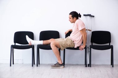 Genç yaralı adam hastane koridorunda sırasını bekliyor.