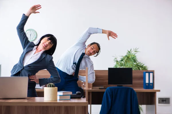 Due dipendenti che fanno esercizi sportivi in ufficio — Foto Stock