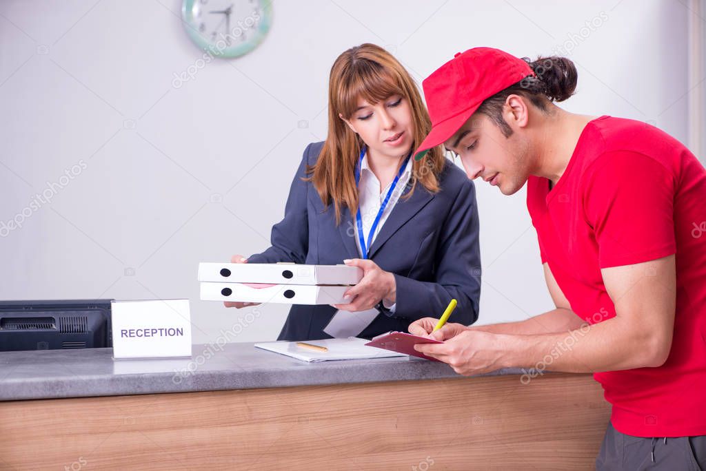 Young male courier delivering pizza to hotels reception