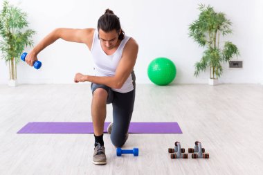 Genç yakışıklı adam içeride spor yapıyor.