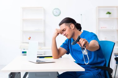 Klinikte çalışan genç erkek doktor.