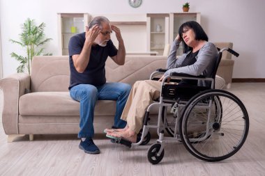 Yaşlı koca engelli eşine bakıyor.