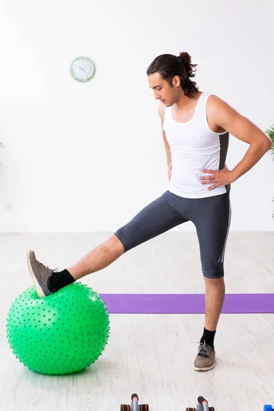 Jovem homem bonito fazendo exercícios esportivos dentro de casa — Fotografia de Stock