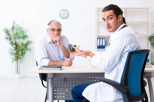 Viejo visitando joven doctor masculino —  Fotos de Stock