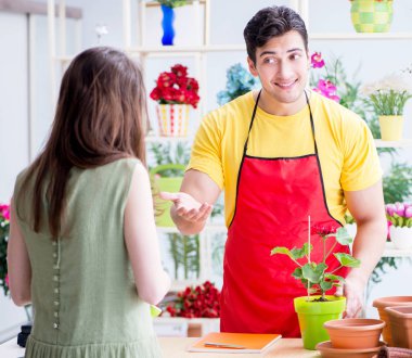 Çiçekçi dükkanında çiçek satıyor.