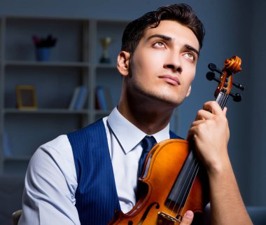 Genç müzisyen evde keman çalıyor.
