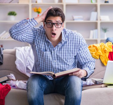 Genç adam dağınık bir odada çalışıyor.