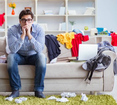 Genç adam dağınık bir odada çalışıyor.