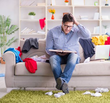 Genç adam dağınık bir odada çalışıyor.