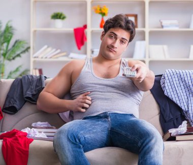 Genç adam dağınık bir odada çalışıyor.