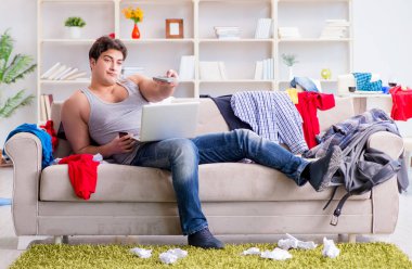 Genç adam dağınık bir odada çalışıyor.