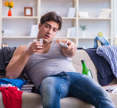 Dağınık bir odada alkol alan genç bir öğrenci.