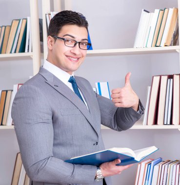 İşadamı öğrenci kütüphanede bir kitap okuyor.