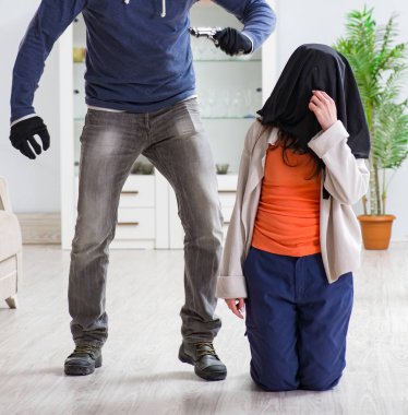 Silahlı bir adam evde genç bir kadına saldırıyor.