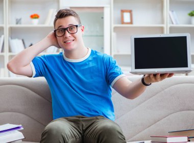 Sınavlara hazırlanan genç öğrenci kanepede ders çalışıyor.