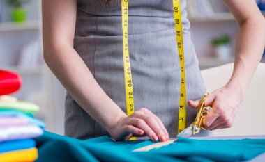 Kadın terzi dikiş dikmek için dikiş dikiyor.