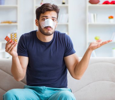 Genç adam estetik cerrahi burnundan sonra evde iyileşiyor.