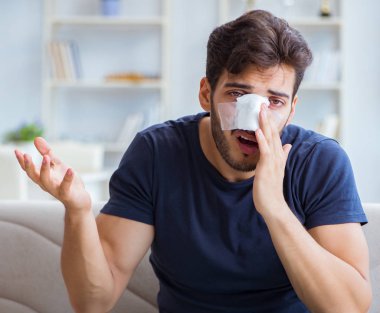 Genç adam estetik cerrahi burnundan sonra evde iyileşiyor.