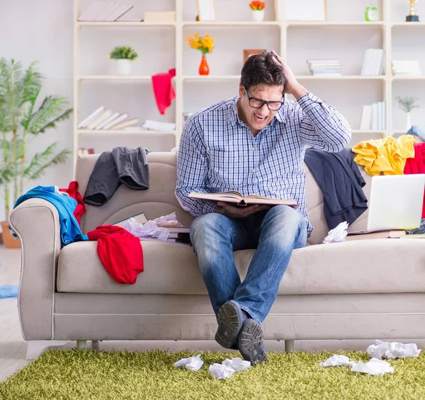 Genç adam dağınık bir odada çalışıyor.