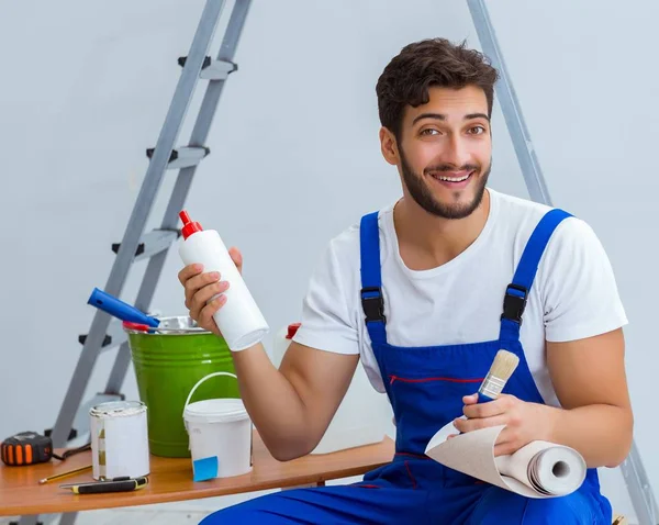 Naprawiający wykonuje remonty w domu z papierową tapetą — Zdjęcie stockowe