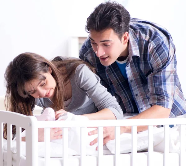 Молоді батьки зі своєю новонародженою дитиною біля ліжка — стокове фото
