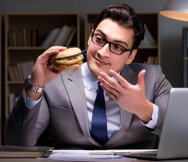 Zakenman die 's avonds laat een hamburger eet — Stockfoto