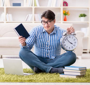 Genç yakışıklı adam evde yerde oturuyor.