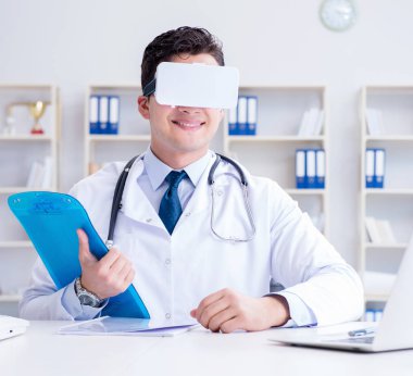 Sanal gerçeklik kulaklığı olan genç doktor ofiste çalışıyor.