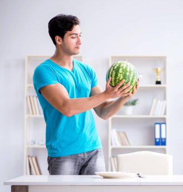 Evde karpuz yiyen bir adam.