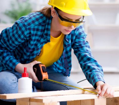 Tamirci kadın marangoz ahşap döşemeleri kesiyor.