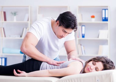 Genç doktor kayropraktik uzmanı kadın hastaya masaj yapıyor.