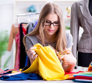 Atölyede çalışan genç bayan terzi yeni elbise üzerinde çalışıyor.