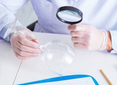 Kriminolog polis kimyageri suç delillerine bakıyor.