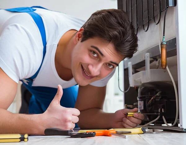 Reparador contratante reparação de geladeira no conceito DIY — Fotografia de Stock