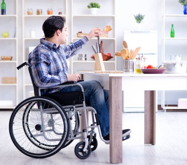 Engelli genç koca mutfakta çalışıyor.