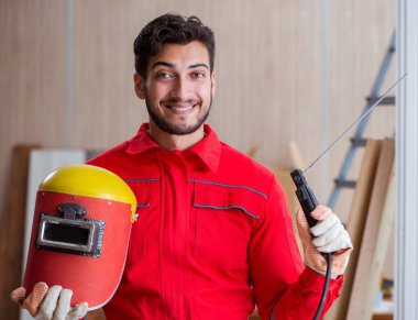 Kaynak tabancası elektrot ve kask takan genç bir tamirci.