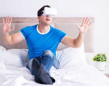 Yatakta sanal gerçeklik başlığı takan genç bir adam.