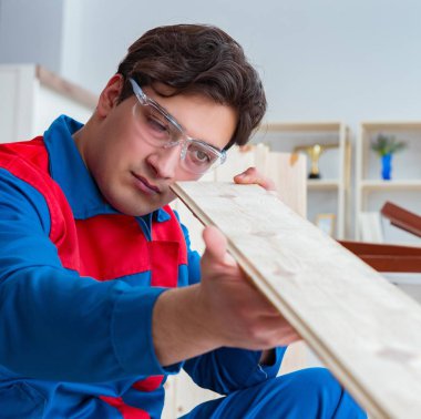 Genç marangoz ahşap kalaslarla çalışıyor.